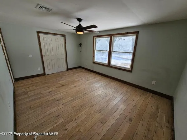 a view of an empty room with window and wooden floor