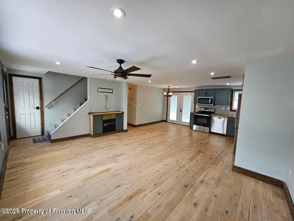 a view of an empty room with a window and wooden floor