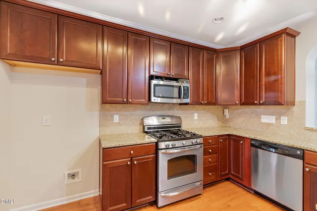 a kitchen with granite countertop wooden cabinets and stainless steel appliances