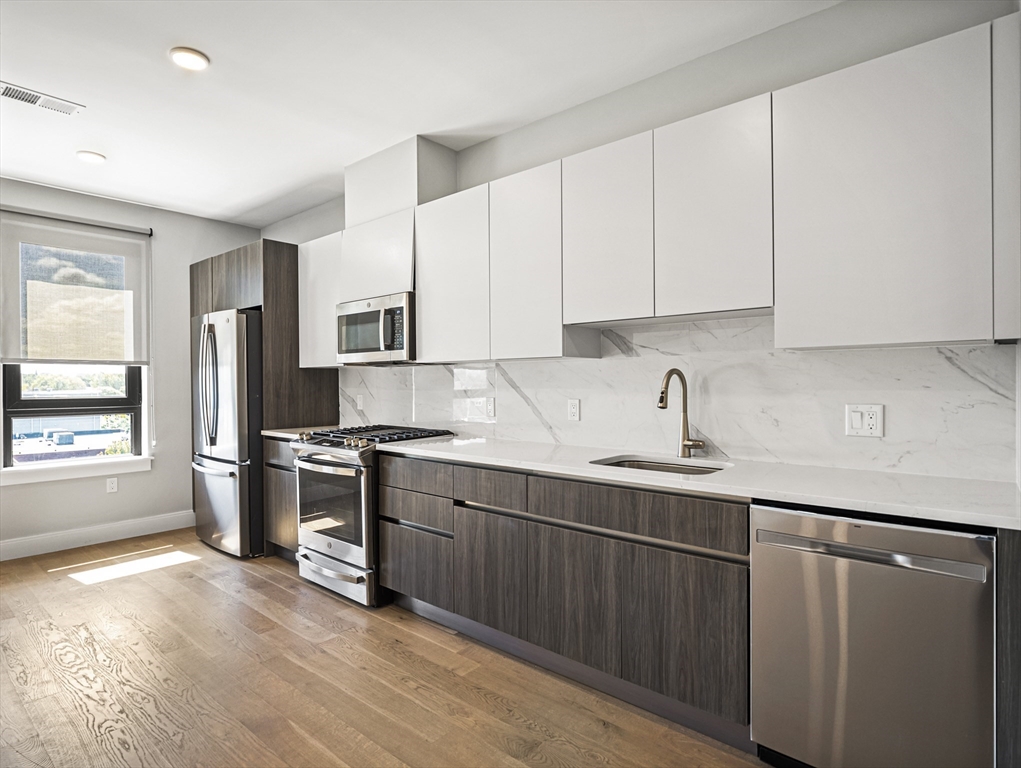 9 Central Street, Unit 405 Somerville, MA 02143 - Photo 2 of 24 a kitchen with stainless steel appliances granite countertop a sink stove and refrigerator