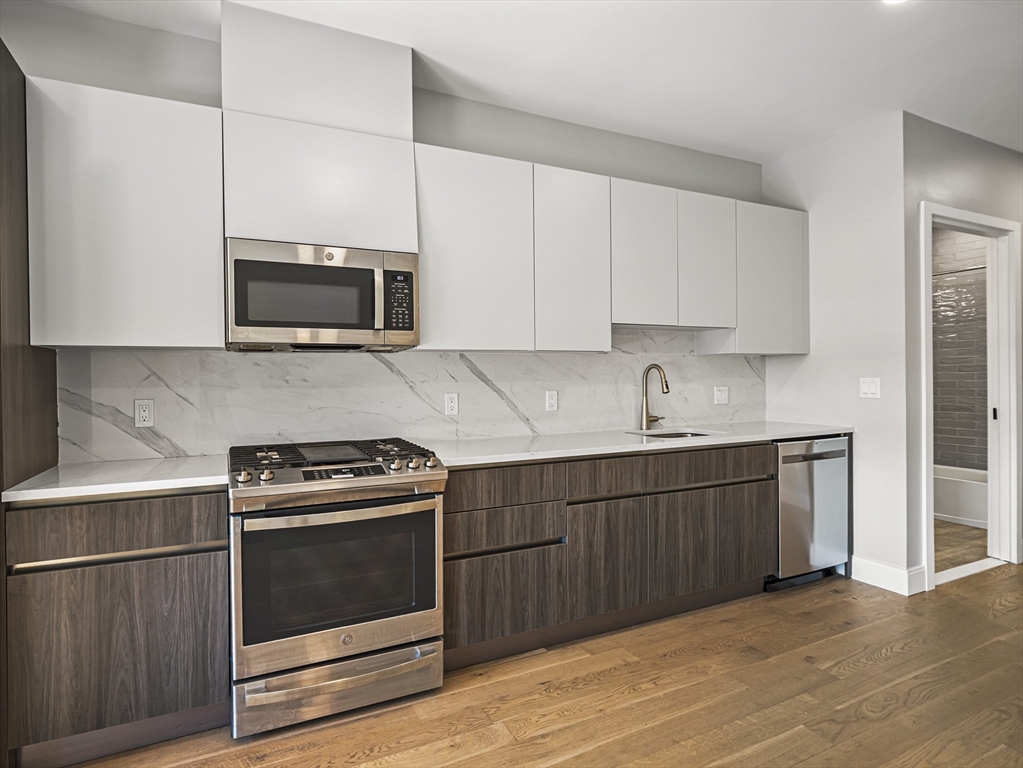 9 Central Street, Unit 405 Somerville, MA 02143 - Photo 4 of 24 a kitchen with granite countertop a stove a microwave a sink and cabinets