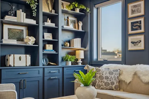 a living room with couches and a bookshelf with wooden floor