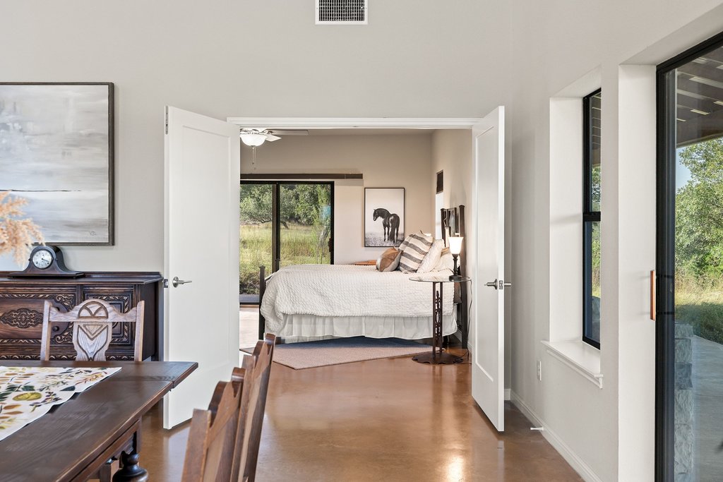 1101 Windy Hills Road Dripping Springs, TX 78620 - Photo 18 of 40 French doors reveal a cozy bedroom with ample natural light and a peaceful view of the outdoors.