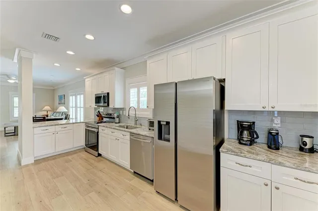 a kitchen with stainless steel appliances granite countertop a refrigerator sink stove and white cabinets