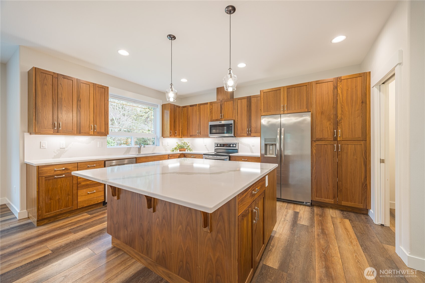 127 Sunrise View Avenue Sequim, WA 98382 - Photo 10 of 31 a kitchen with stainless steel appliances granite countertop a sink a refrigerator a stove a kitchen island with wooden floor and cabinets