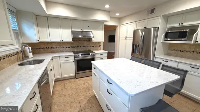 a kitchen with stainless steel appliances kitchen island granite countertop a sink stove refrigerator and cabinets
