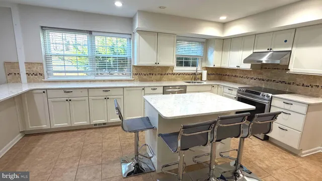 a kitchen with a stove a sink cabinets and wooden floor