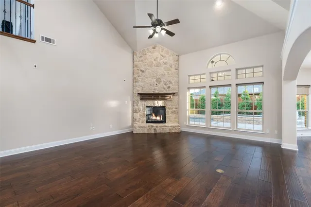 a view of an empty room with wooden floor fireplace and a window