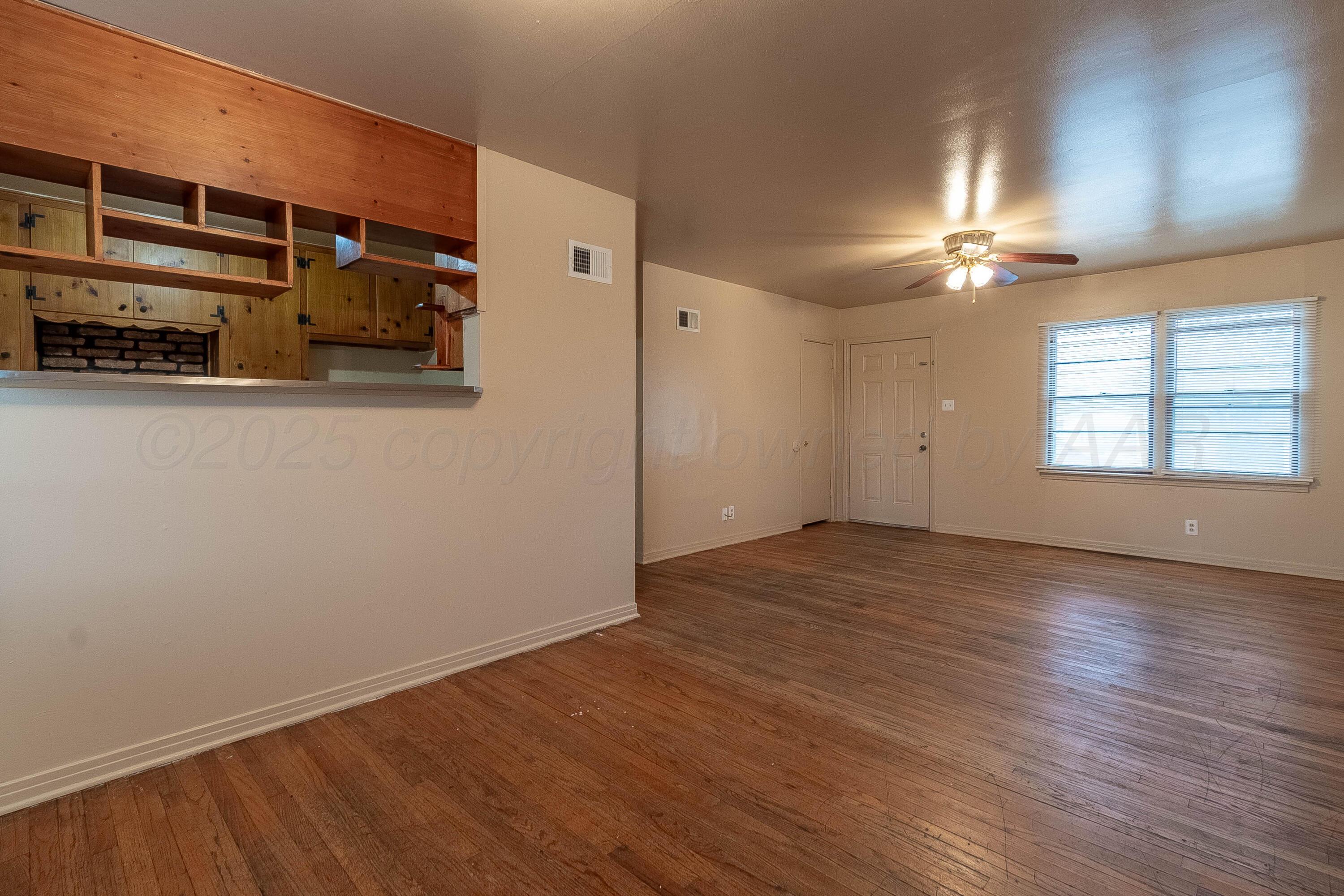2414 Orange Street Amarillo, TX 79107 - Photo 3 of 16 an empty room with wooden floor closet and windows