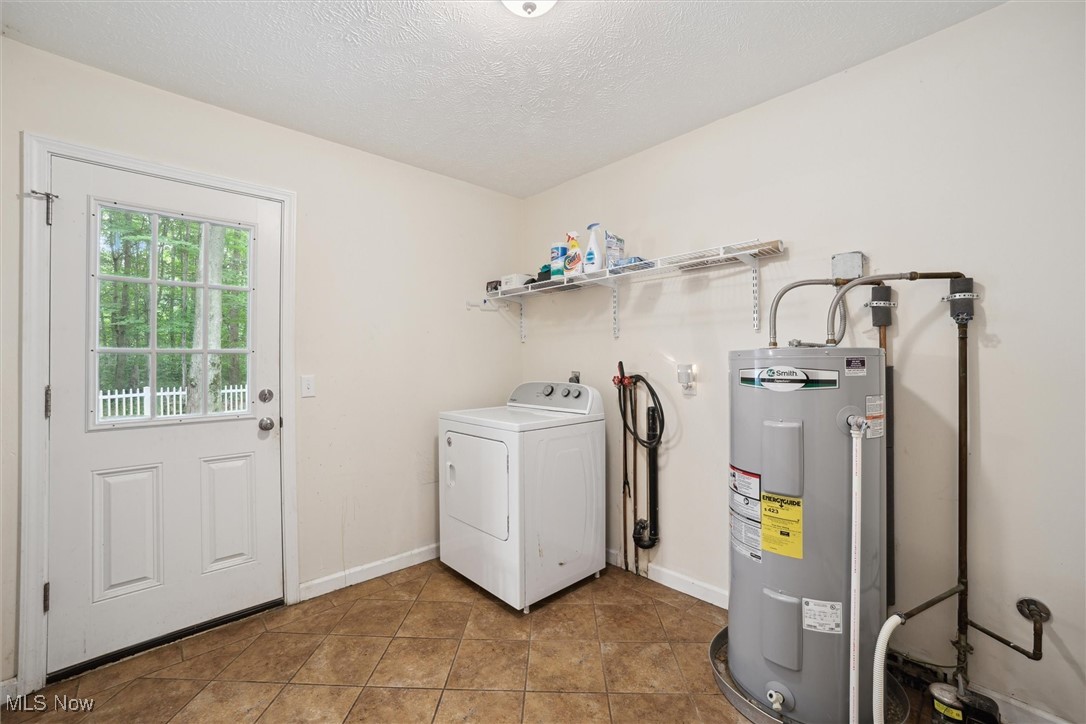 938 Long Shadow Lane Rome, OH 44085 - Photo 42 of 48 Laundry area featuring washer / dryer, water heater, tile patterned floors, and a textured ceiling