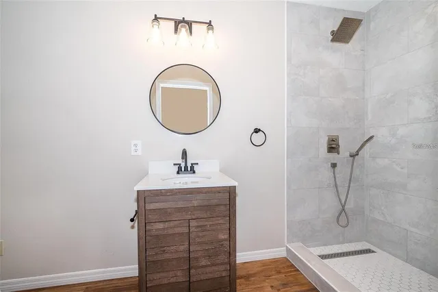 a bathroom with a granite countertop sink a mirror and shower