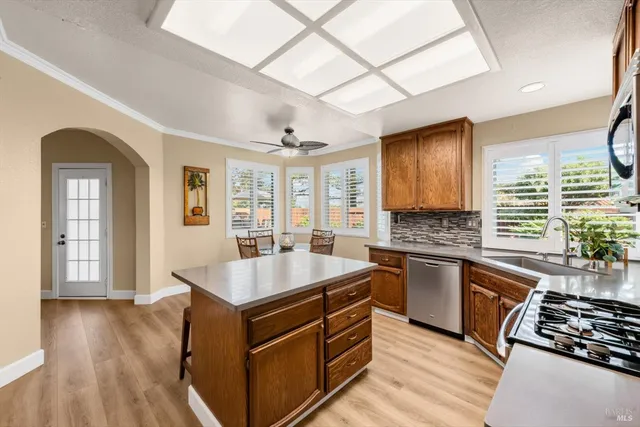 a kitchen with stainless steel appliances granite countertop a stove a refrigerator a sink a stove and island with wooden floor