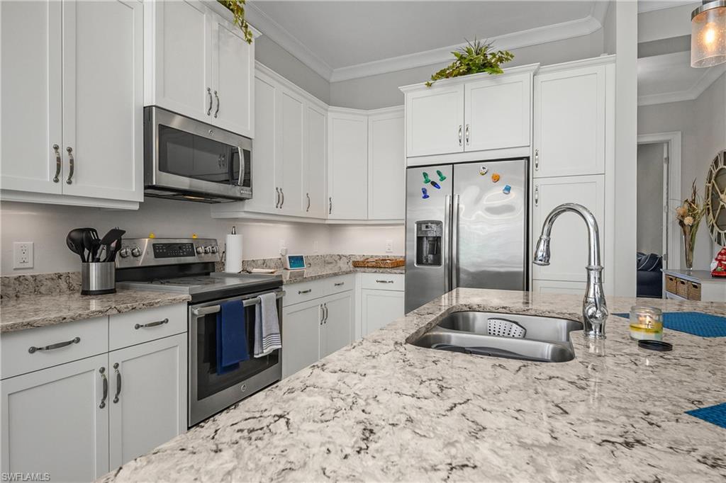 6552 Dominica Drive, Unit 101 Naples, FL 34113 - Photo 8 of 50 a kitchen with granite countertop a sink stainless steel appliances and white cabinets