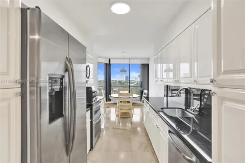 a kitchen with stainless steel appliances a refrigerator a stove a sink and white cabinets