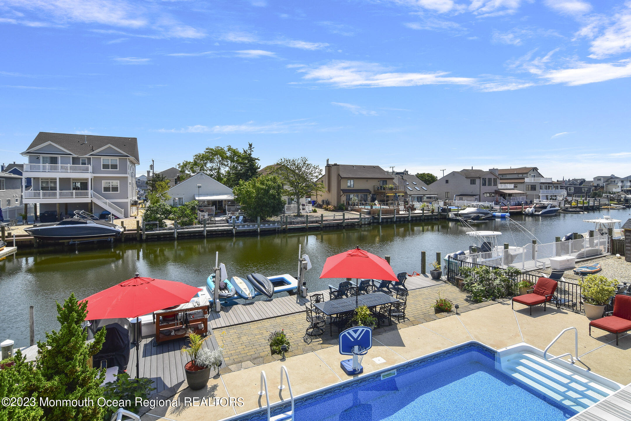 8 Rochester Drive Brick, NJ 08723 - Photo 33 of 41 a view of a lake with a table and chairs under an umbrella on wooden deck