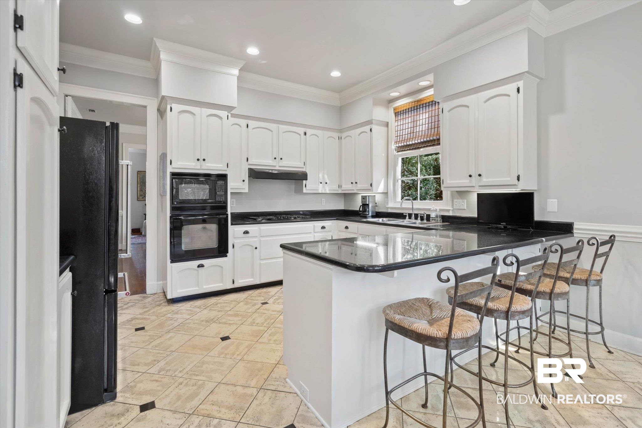 3615 Stein Street Mobile, AL 36608 - Photo 13 of 44 Kitchen featuring a peninsula, a breakfast bar area, crown molding, white cabinets, and black appliances