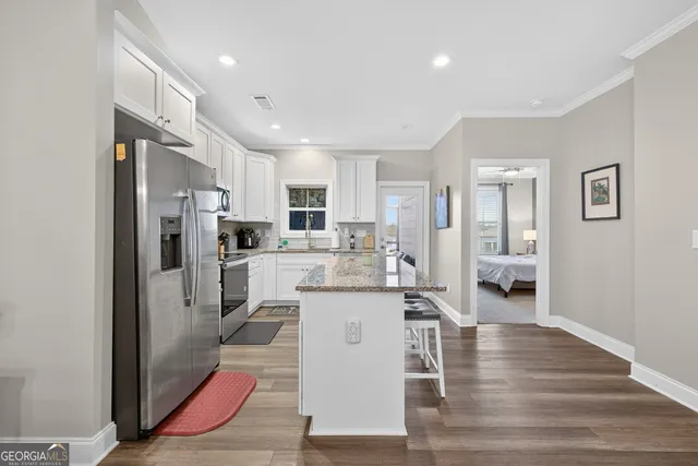 a kitchen with stainless steel appliances kitchen island granite countertop a refrigerator and a stove top oven