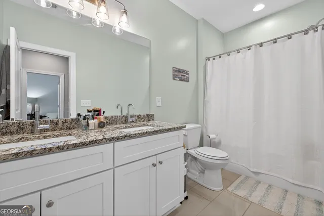 a bathroom with a granite countertop sink toilet and mirror