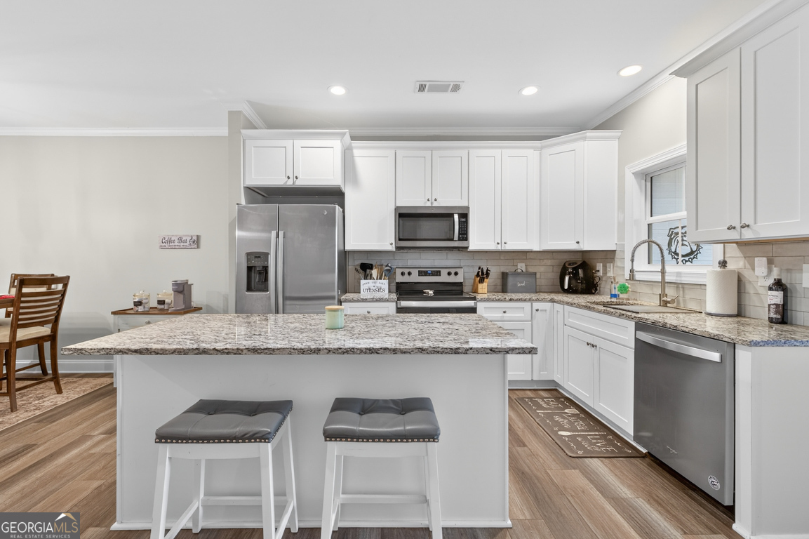 110 Magnolia Place Homer, GA 30547 - Photo 9 of 42 a kitchen with stainless steel appliances granite countertop a stove a sink a microwave a refrigerator and white cabinets with wooden floor
