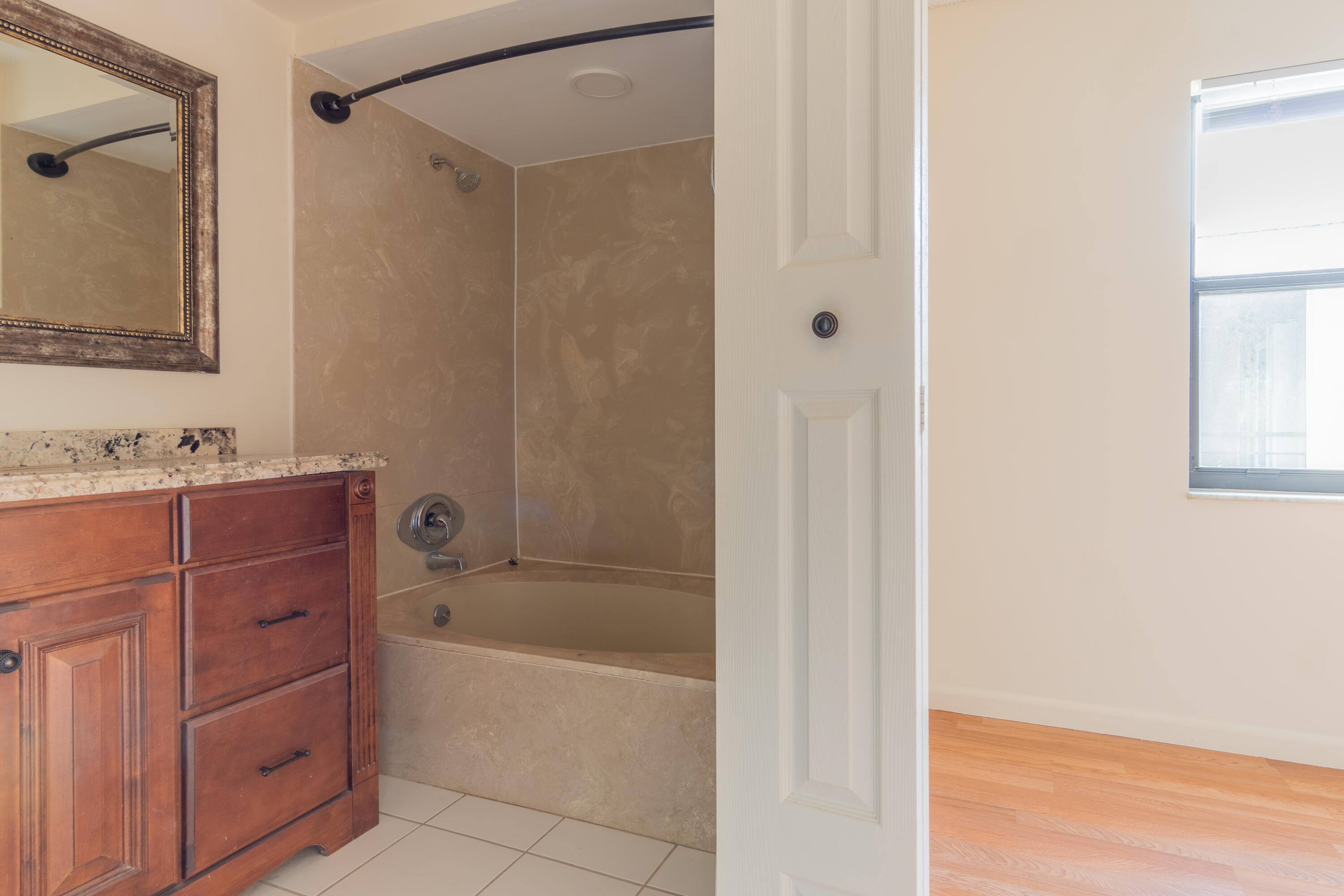 9355 Southwest 8th Street, Unit 406 Boca Raton, FL 33428 - Photo 11 of 22 a bathroom with a bathtub sink vanity and mirror