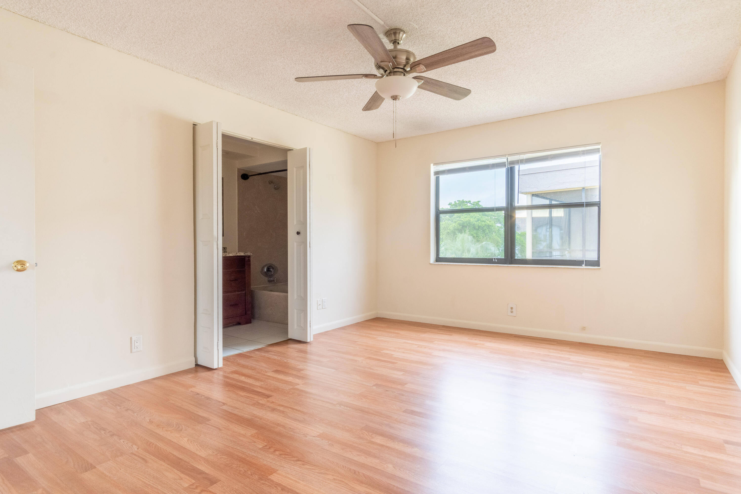9355 Southwest 8th Street, Unit 406 Boca Raton, FL 33428 - Photo 8 of 22 an empty room with wooden floor ceiling fan and windows