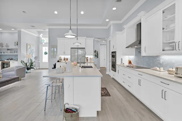 a large white kitchen with lots of counter space dining table and stainless steel appliances
