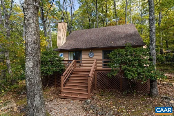 a view of a house with a yard plants and large tree
