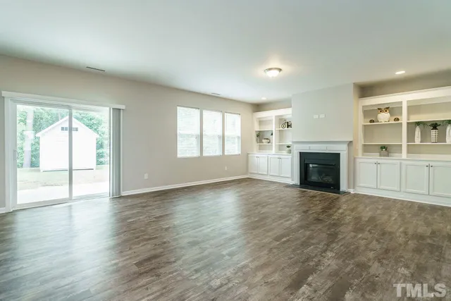 an empty room with windows and fireplace