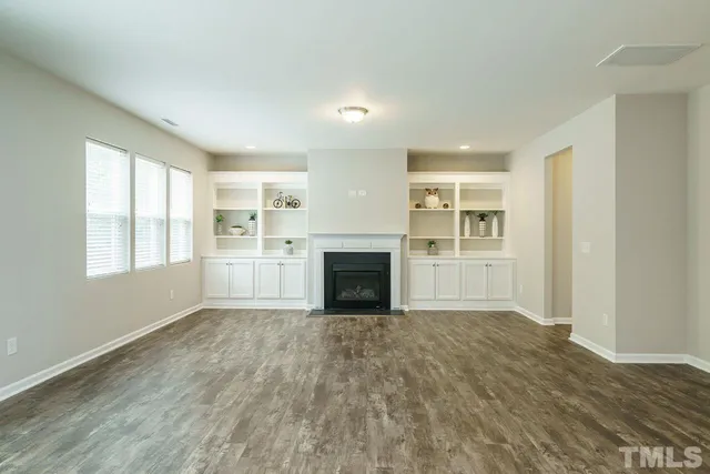 a view of empty room with a fireplace and wooden floor