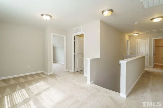 a view of an empty room with wooden floor and a kitchen
