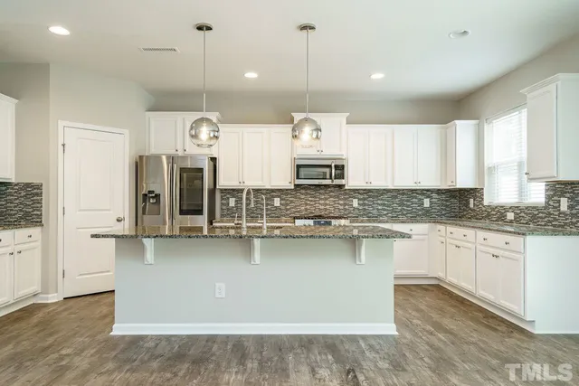 a kitchen with stainless steel appliances granite countertop a sink a stove and a wooden floors