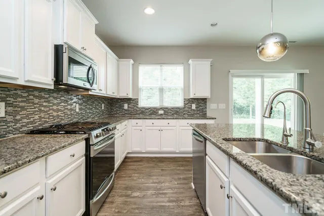a kitchen with granite countertop a sink stainless steel appliances and cabinets