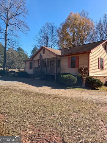 a front view of a house with a yard covered with snow and trees