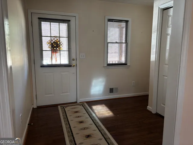 an empty room with wooden floor windows and closet