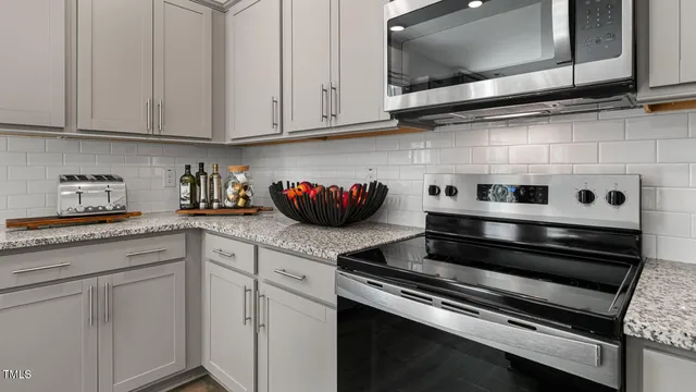 a kitchen with stainless steel appliances granite countertop white cabinets and stove top oven with a dishwasher