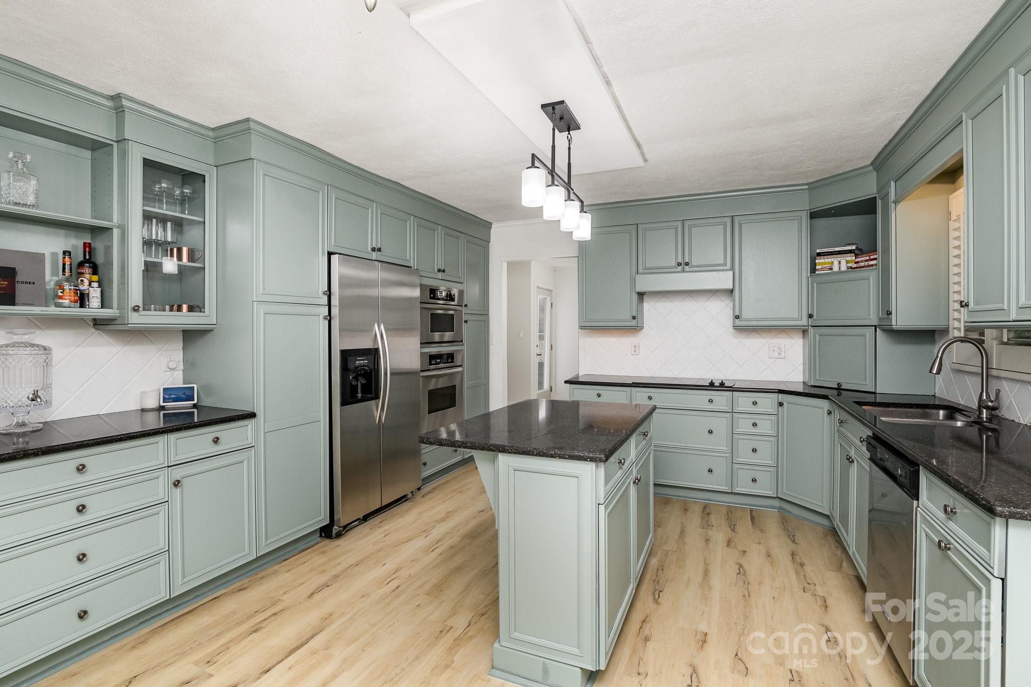 a kitchen with granite countertop a sink stove and refrigerator