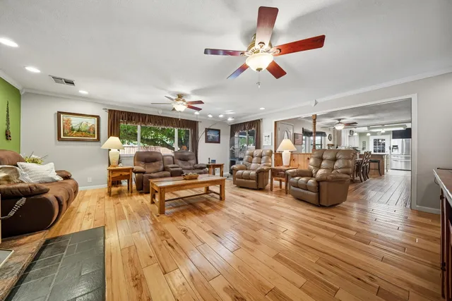 a living room with furniture kitchen view and a wooden floor