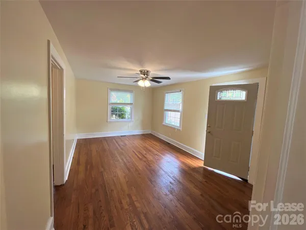a view of an empty room with wooden floor and a window