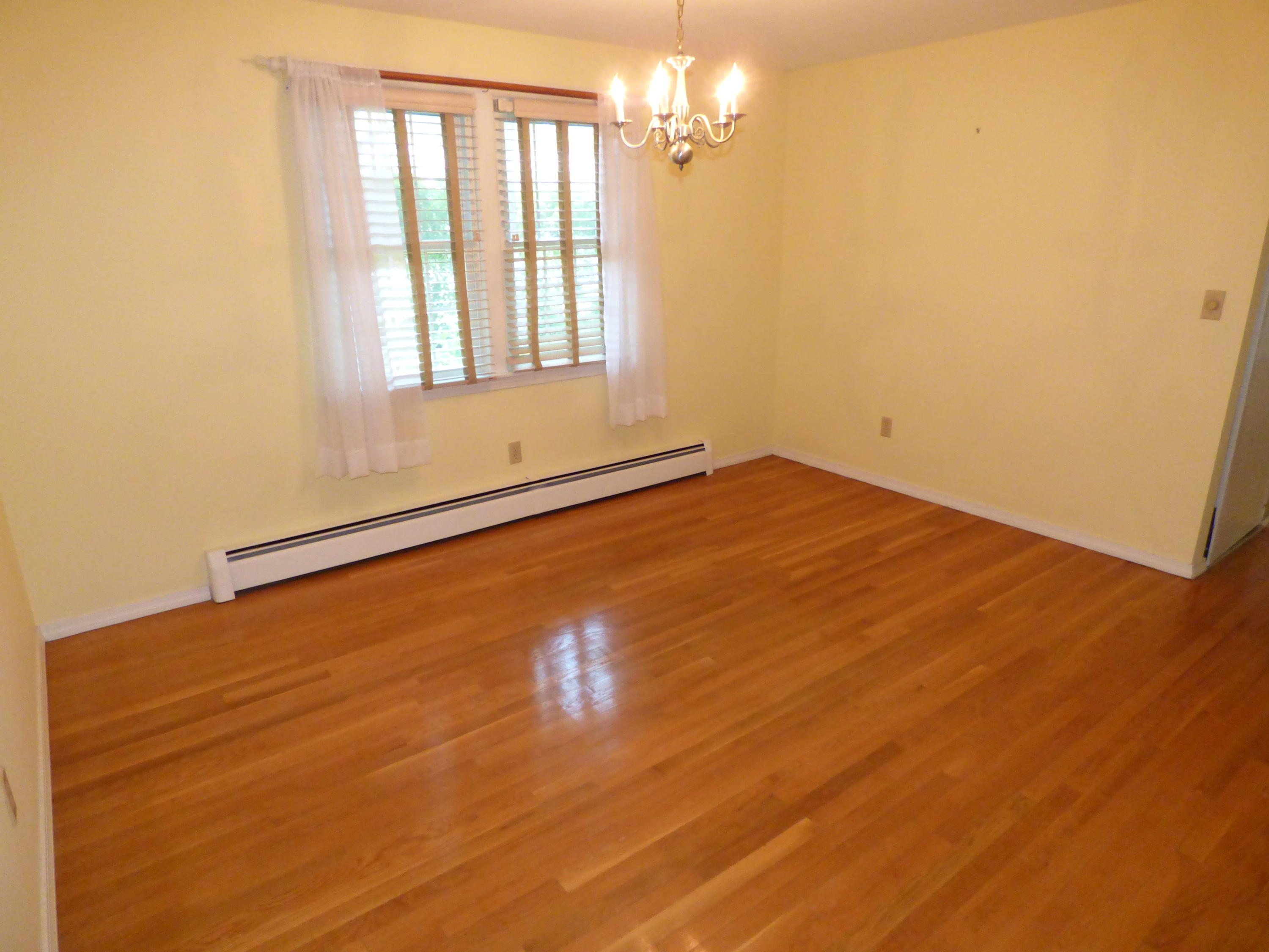 195 Ansel Howland Road Centerville, MA 02632 - Photo 8 of 22 an empty room with wooden floor and windows