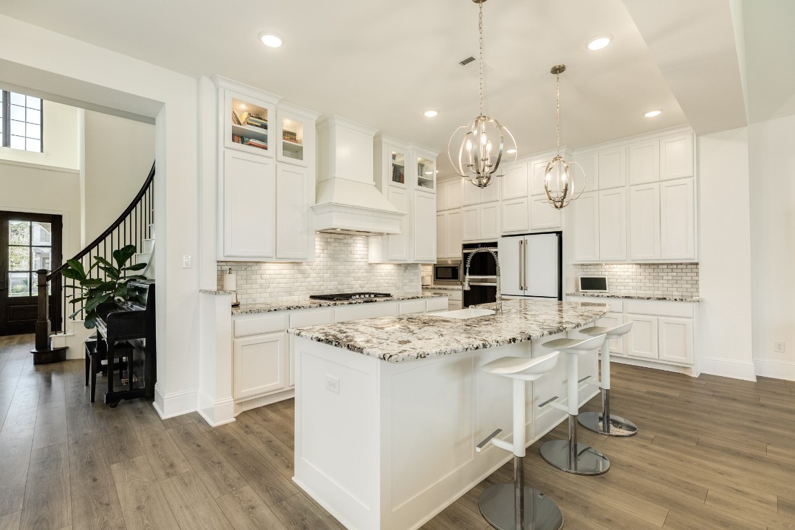 10102 Brush Way Rosharon, TX 77583 - Photo 14 of 50 The island has been extended to accommodate four barstools. Decorative cabinets are mounted on top for displaying dishes, and the island is illuminated by beautiful pendant lights.