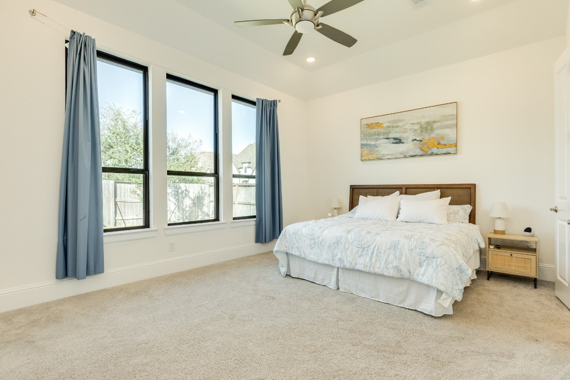 10102 Brush Way Rosharon, TX 77583 - Photo 21 of 50 Primary bedroom located off the family area with backyard views. The room features a spacious layout, beautiful carpet, a ceiling fan, and oversized windows.