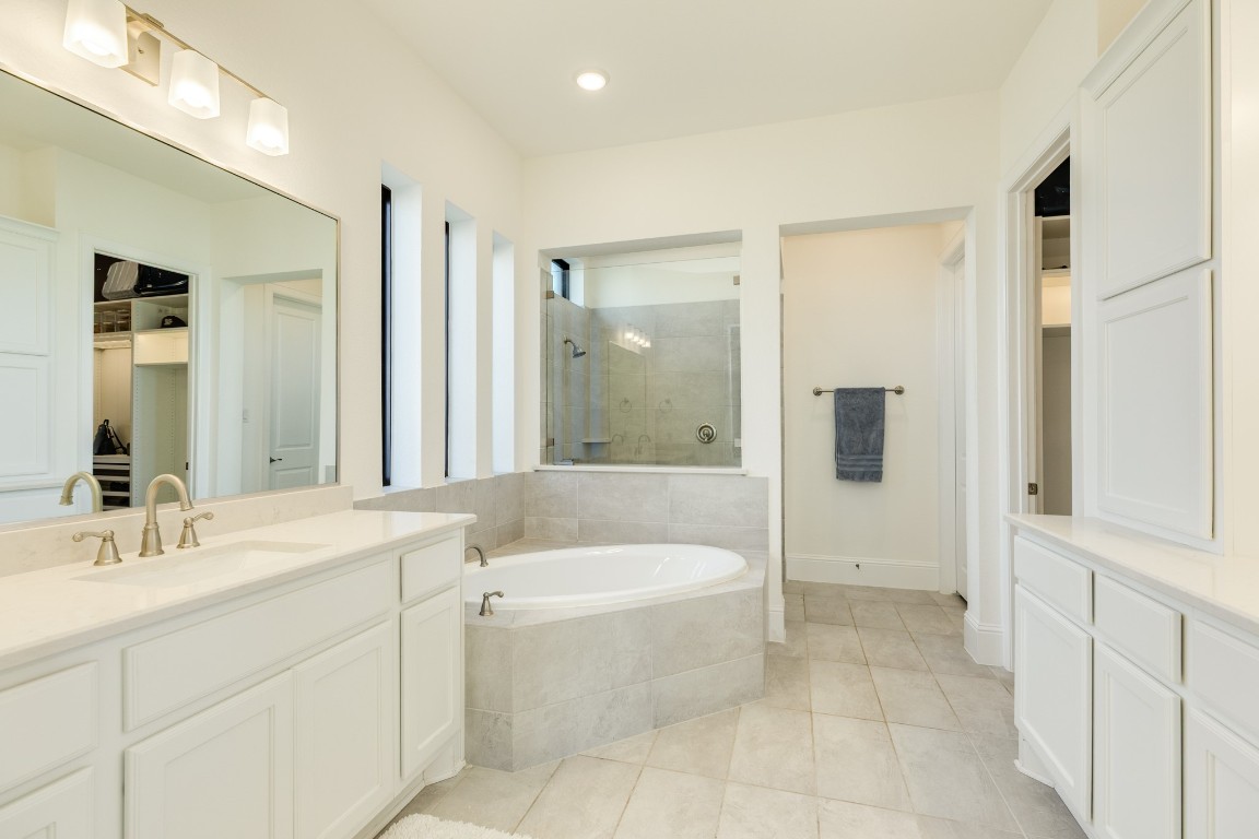 10102 Brush Way Rosharon, TX 77583 - Photo 23 of 50 Primary bathroom features double vanities, tile flooring, a soaking tub, and a walk-in glass shower.