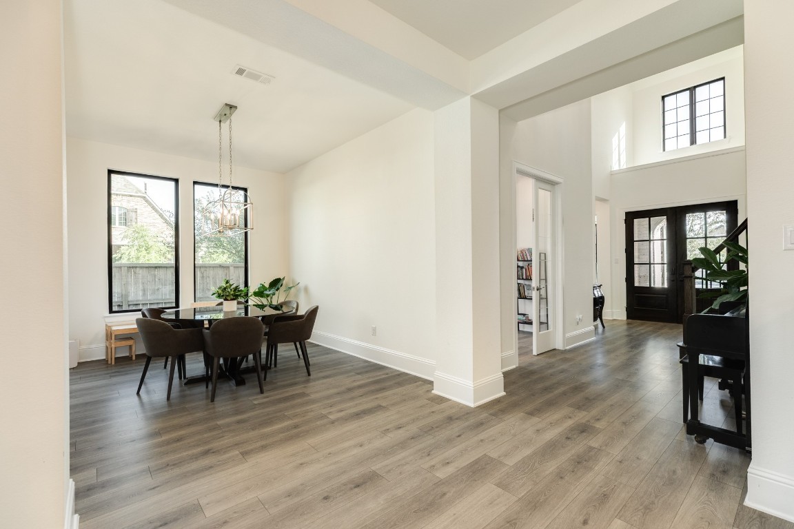 10102 Brush Way Rosharon, TX 77583 - Photo 10 of 50 The formal dining room features wooden floors, a modern chandelier, and ample space for a table accommodating eight guests.