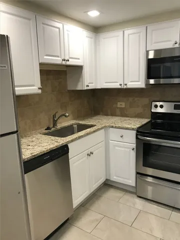 a kitchen with granite countertop white cabinets and stainless steel appliances