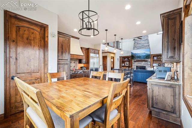 13665 Random Ridge View Colorado Springs, CO 80921 - Photo 14 of 49 Dining space featuring a stone fireplace, a chandelier, and dark hardwood / wood-style flooring