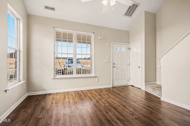 an empty room with wooden floor and windows