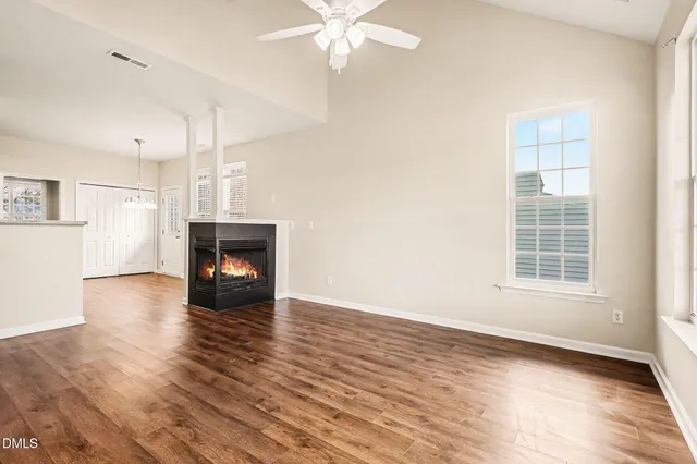 an empty room with wooden floor fireplace and windows