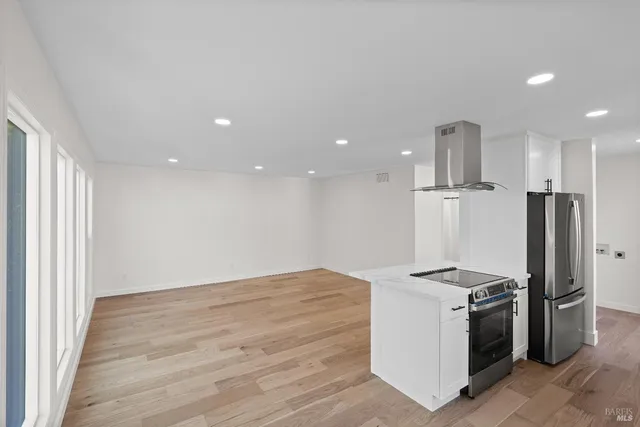 a view of kitchen with refrigerator stove and wooden floor
