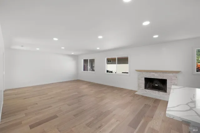 a view of empty room with wooden floor and fireplace