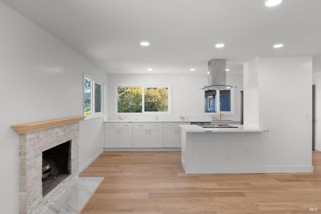 a open kitchen with kitchen island a sink wooden floor and a fireplace